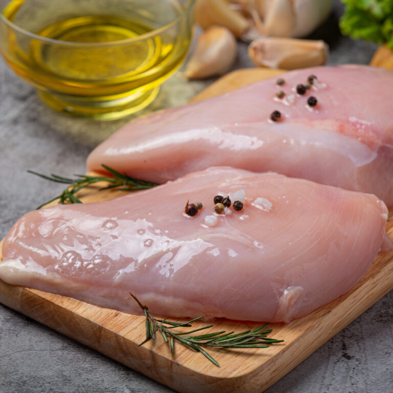 Raw chicken breast on the dark background.