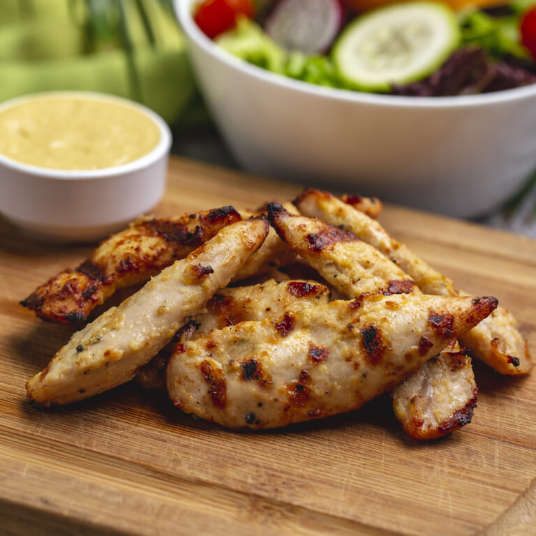 grilled chicken breast on wooden board side view