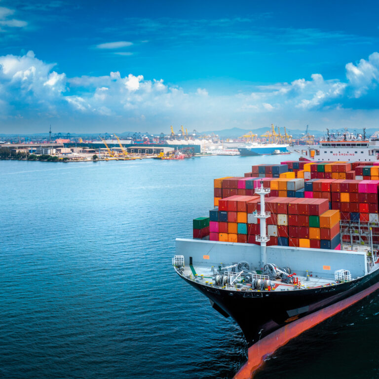 Aerial side view of cargo ship carrying container and running fo
